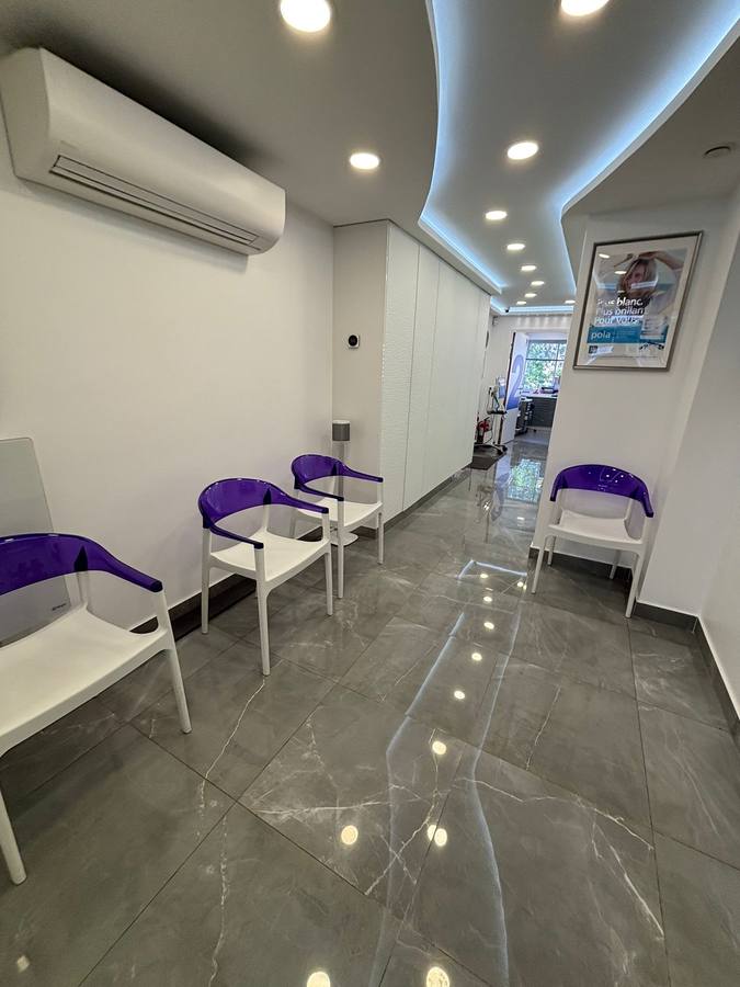 Salle d'attente d'un cabinet dentaire rénové, faux-plafond courbe à éclairage indirect et sol grès cérame effet marbre
