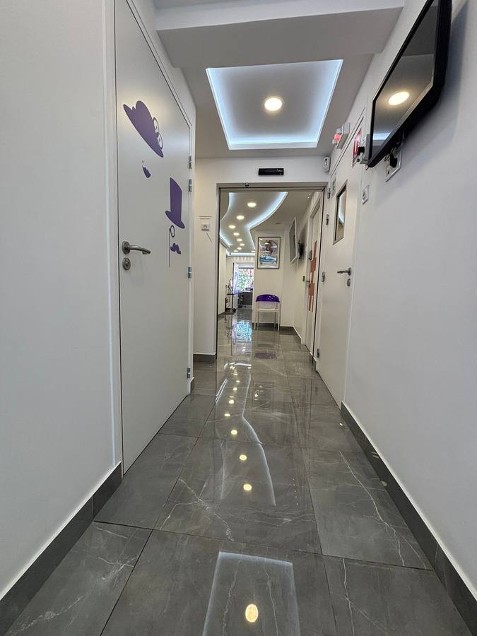 Couloir de cabinet dentaire avec faux-plafond lumineux et sol grès cérame poli