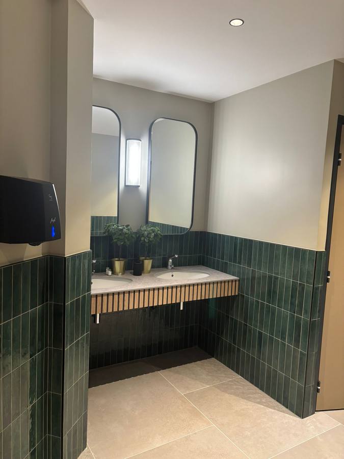 Sanitaires en faïence verte posée verticalement, double vasque sur plan terrazzo