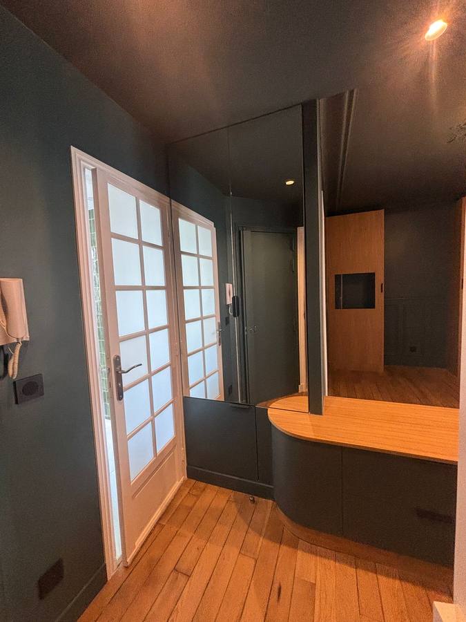 Entrée aux murs et plafond sombres, meuble courbe sur mesure et miroir toute hauteur