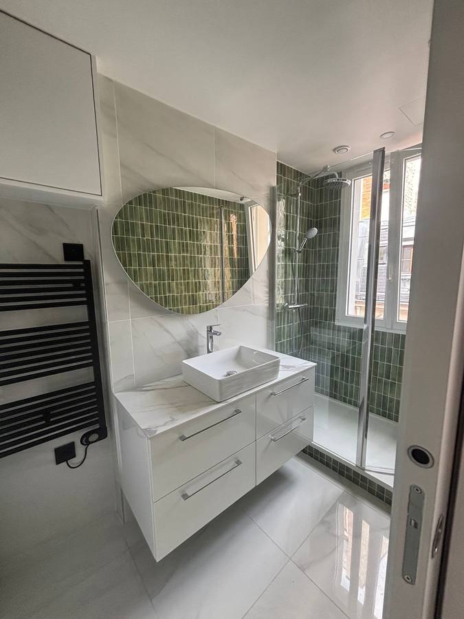 Salle d'eau avec douche en faïence verte, meuble vasque suspendu et miroir organique