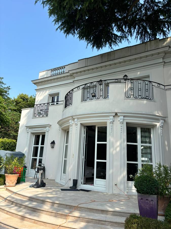Façade blanche d'une maison de maître après ravalement, balcons en ferronnerie et consoles sculptées
