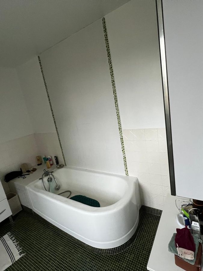 Salle de bains avant travaux : ancienne baignoire et mosaïque verte
