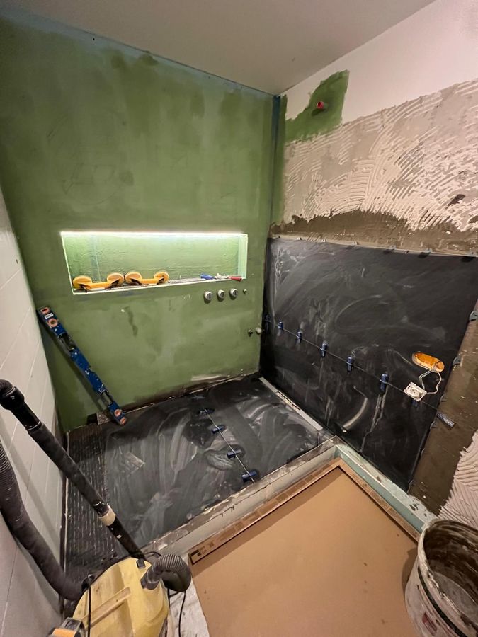 Douche à l'italienne terminée : grès cérame grand format, niche en mosaïque et robinetterie laiton